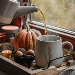 théière qui sert un thé dans un décor automne avec une citrouille et bougie