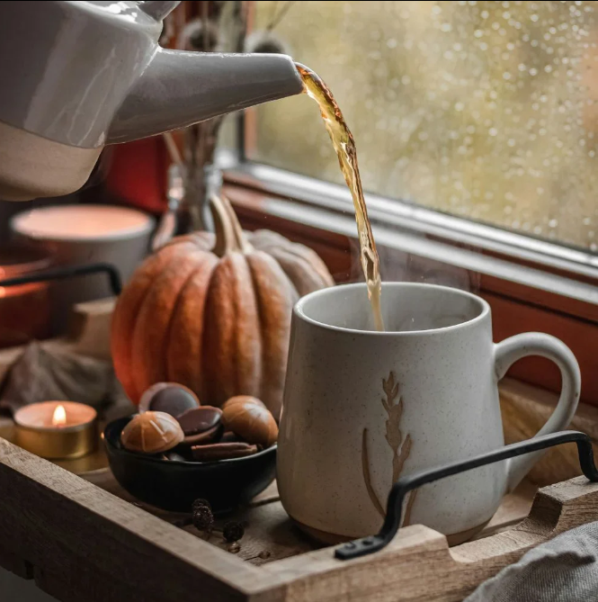 théière qui sert un thé dans un décor automne avec une citrouille et bougie